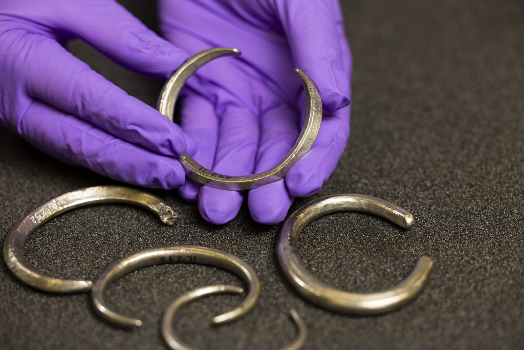 Assistant Curator Craig Angus with silver arm rings from the Burray Hoard. Photo © Duncan McGlynn