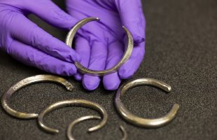 Assistant Curator Craig Angus with silver arm rings from the Burray Hoard. Photo © Duncan McGlynn